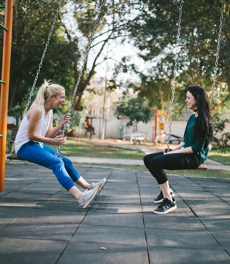 Two Women Swing In A Park